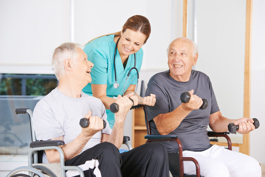 two senior men in wheelchairs lifting dumbbells during physiotherapy